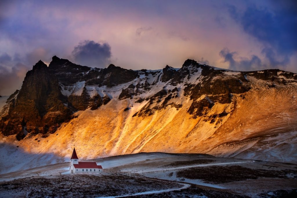 A small church sits on top of a snowy mountain.