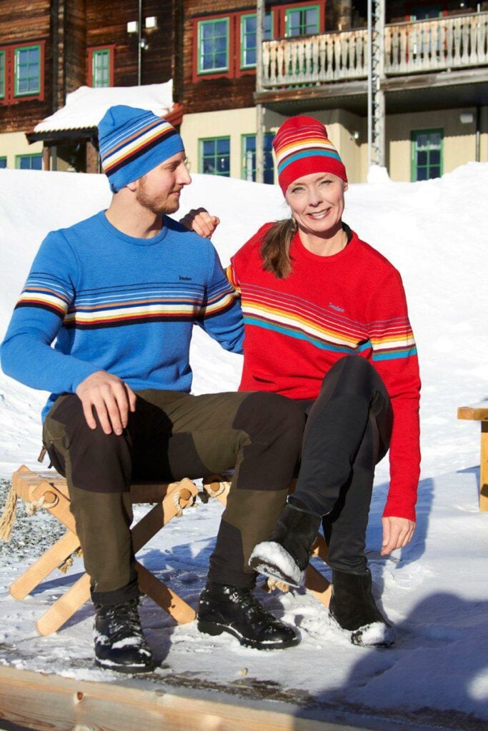 A man and a woman sitting on a bench in the snow.